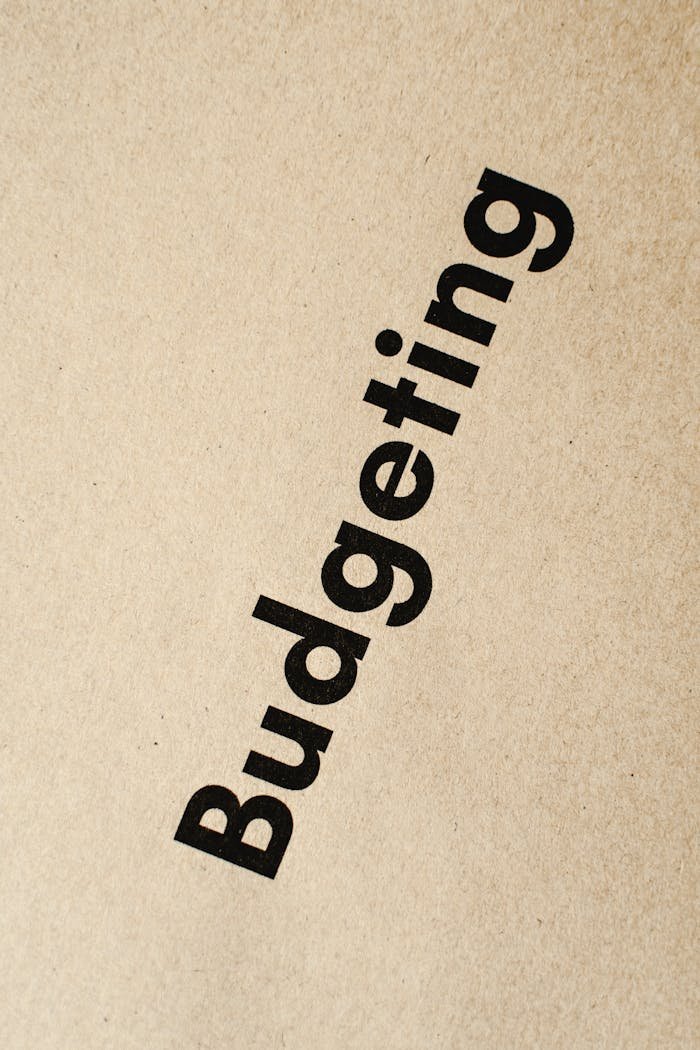 about-us Detailed close-up of the word 'Budgeting' printed on brown textured paper.